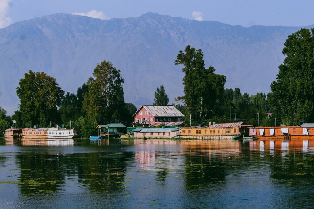pexels-photo-13827306-13827306 Scenic view of Dal Lake in Kashmir, showcasing houseboats and mountains under a clear sky.